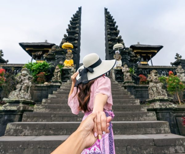 Women tourists holding man's hand and leading him to Besakih temple in Bali, Indonesia.
